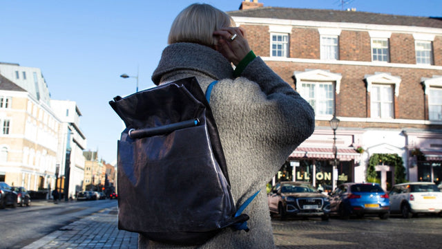 black faux leather backpack modelled on a quaint city