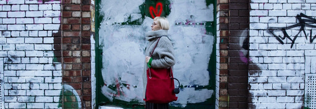 red ditto convertible city bag modelled in front of graffiti
