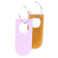 Two reversible linoleum earrings, one showing the back in lilac, the other the front in orange.