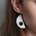 Close-up of a person wearing a unique earring with a patterned design.