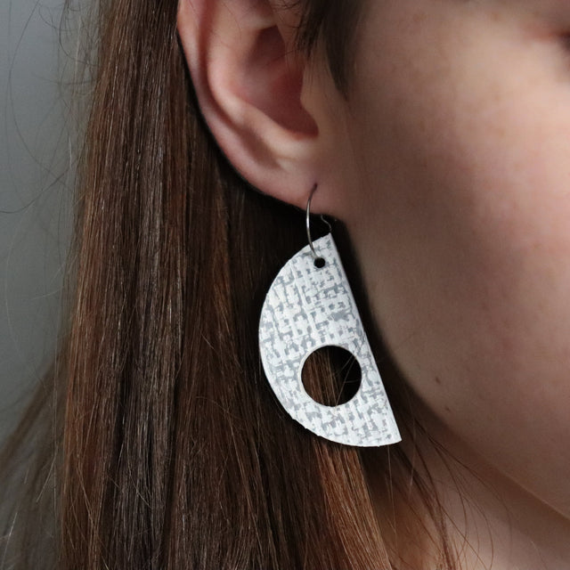 Close-up of a person wearing a unique earring with a patterned design.