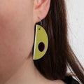 moss green earring with a circle cutout worn by a person