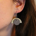 Close-up of an earring worn by a person with brown hair.