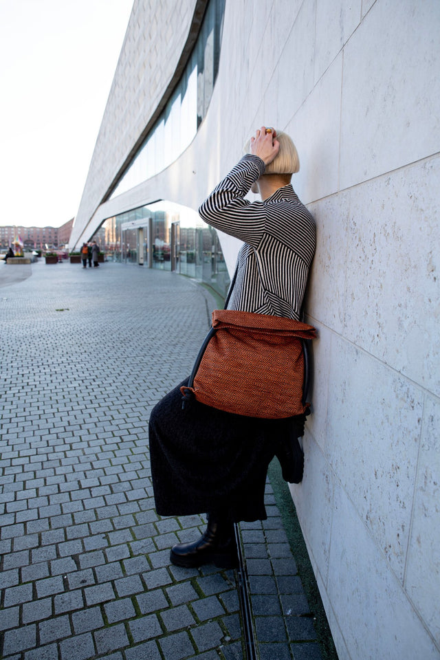 orange & black geometric bag modelled against contemporary architecture