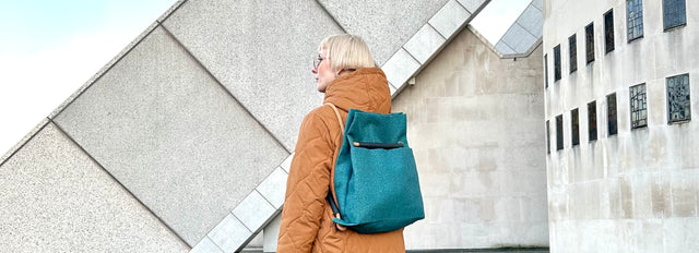 teal ditto backpack with brutalist architecture